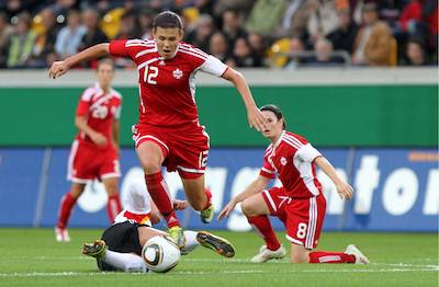 Christine Sinclair balle au pied avec la sélection nationale canadienne lors d'une rencontre face à l'Allemagne.